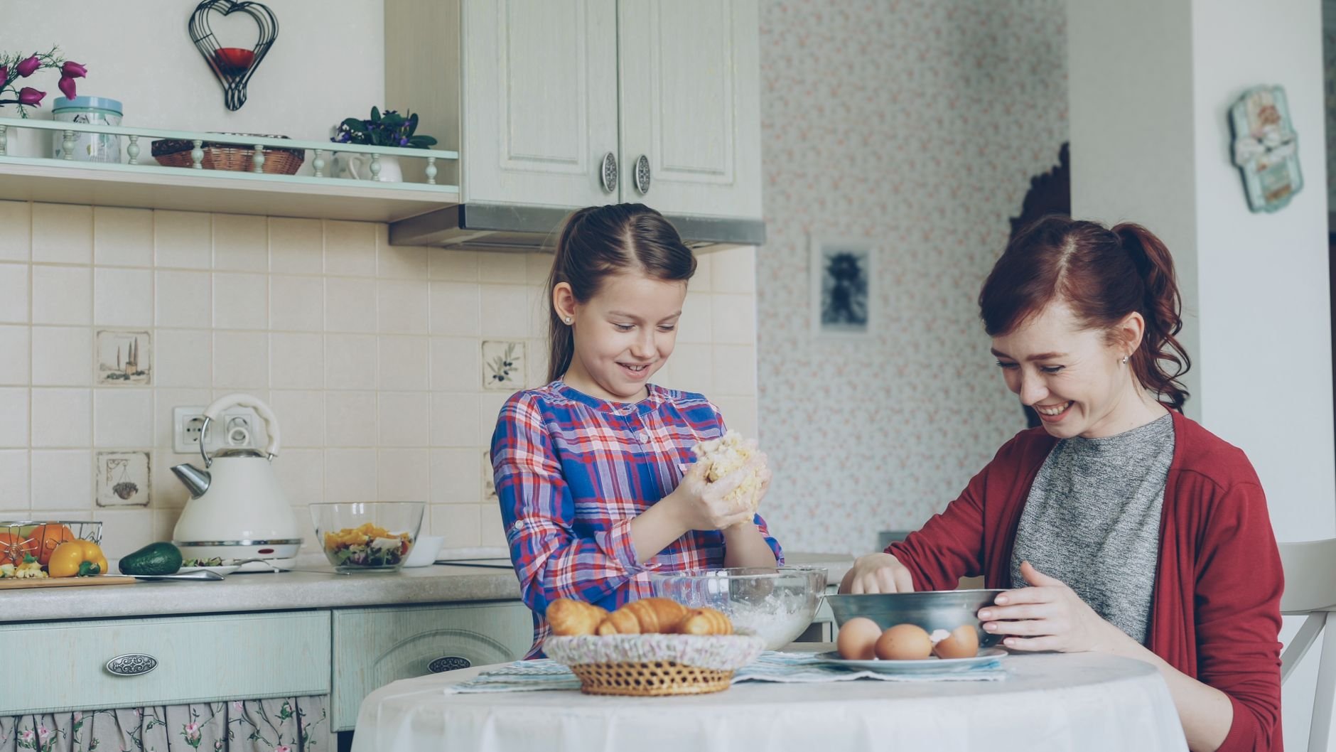 A mother and daughter joyfully bake together in a warm, inviting kitchen
