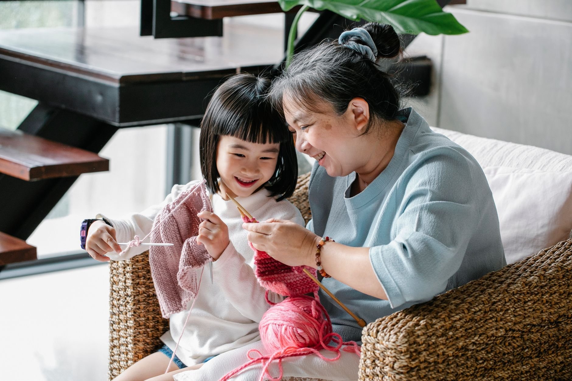 Grandparent and grandchild learning a craft skill together at home